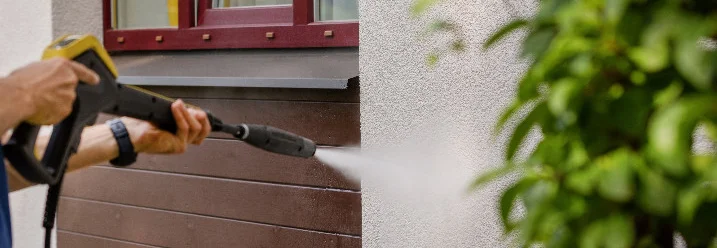 Person reinigt Fassade mit Hochdruckreiniger